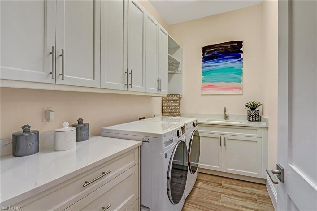 Washroom with separate washer and dryer, sink, cabinets, and light wood-type flooring
