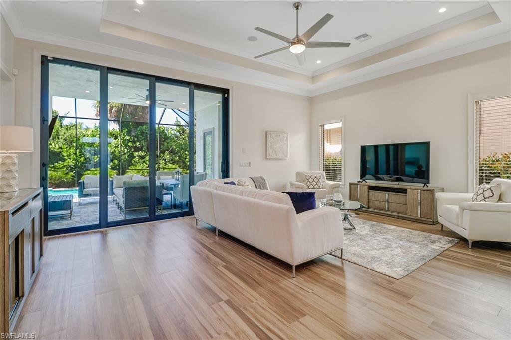 Living room with a tray ceiling, crown molding, and light hardwood / wood-style flooring
