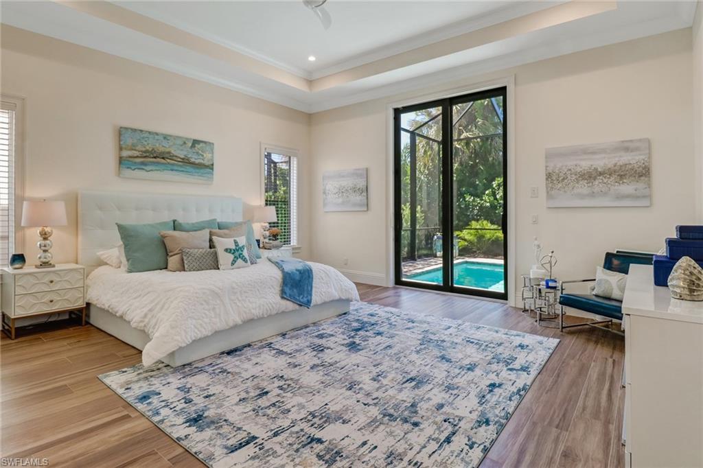Bedroom featuring access to exterior, ornamental molding, wood-type flooring, and a tray ceiling