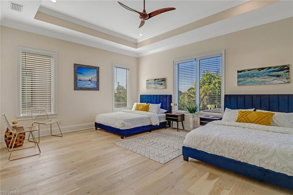 Bedroom with ceiling fan, a raised ceiling, crown molding, and light hardwood / wood-style flooring