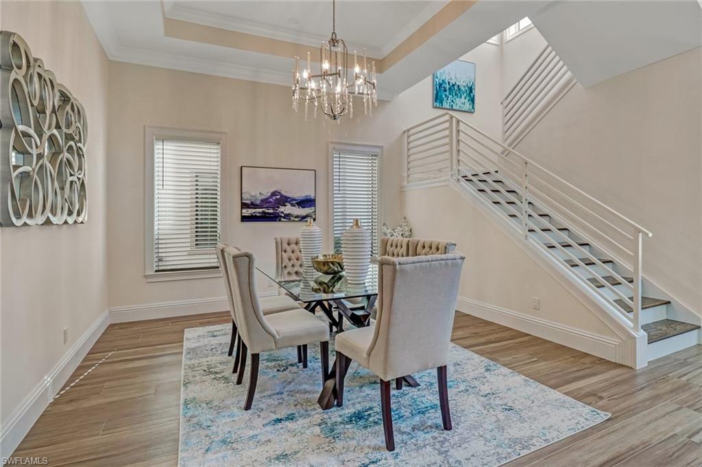 Dining space with a chandelier, light wood-type flooring, ornamental molding, and a tray ceiling