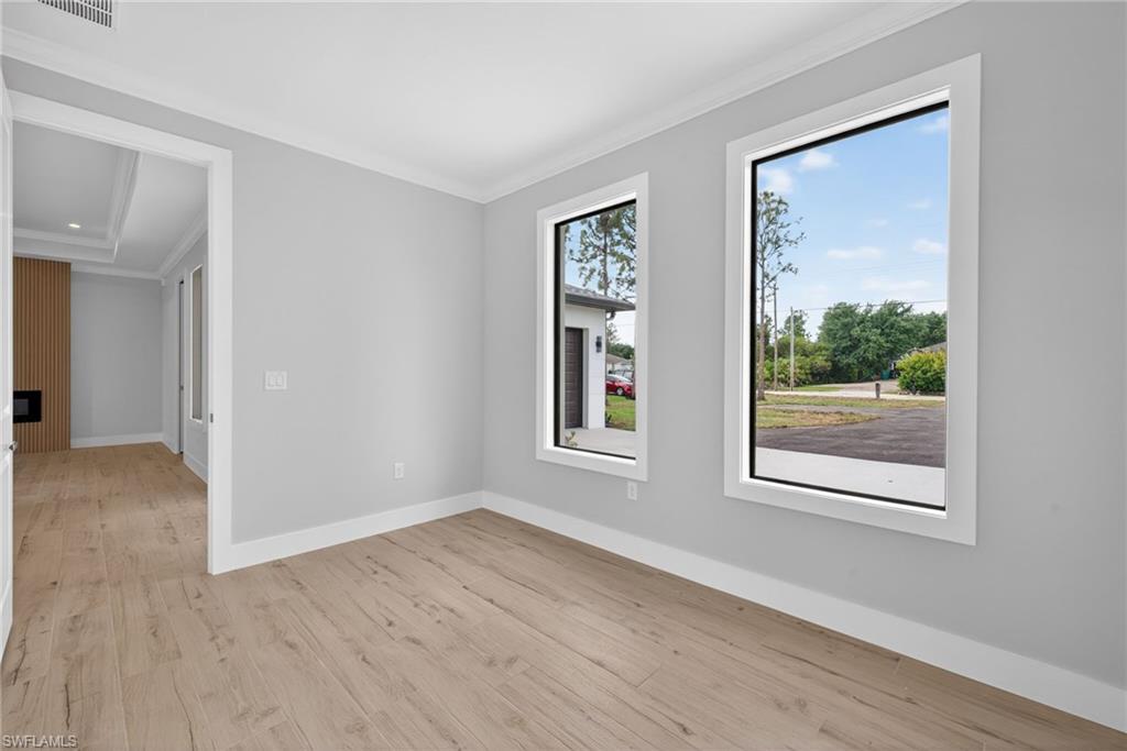 Bright room featuring two large windows with white trim, light wood-finish flooring, and light gray painted walls