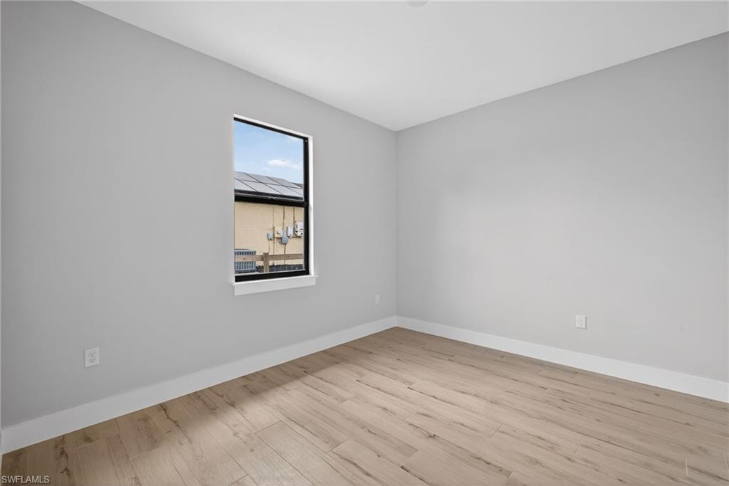 Light-filled interior space featuring wood-finish flooring, crisp white baseboards, and a single black-framed window