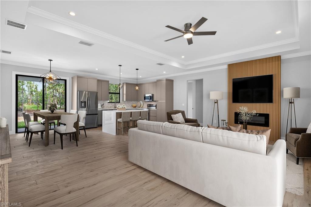 Open-concept living space featuring wood-finish flooring, a contemporary fireplace, and a kitchen island with seating