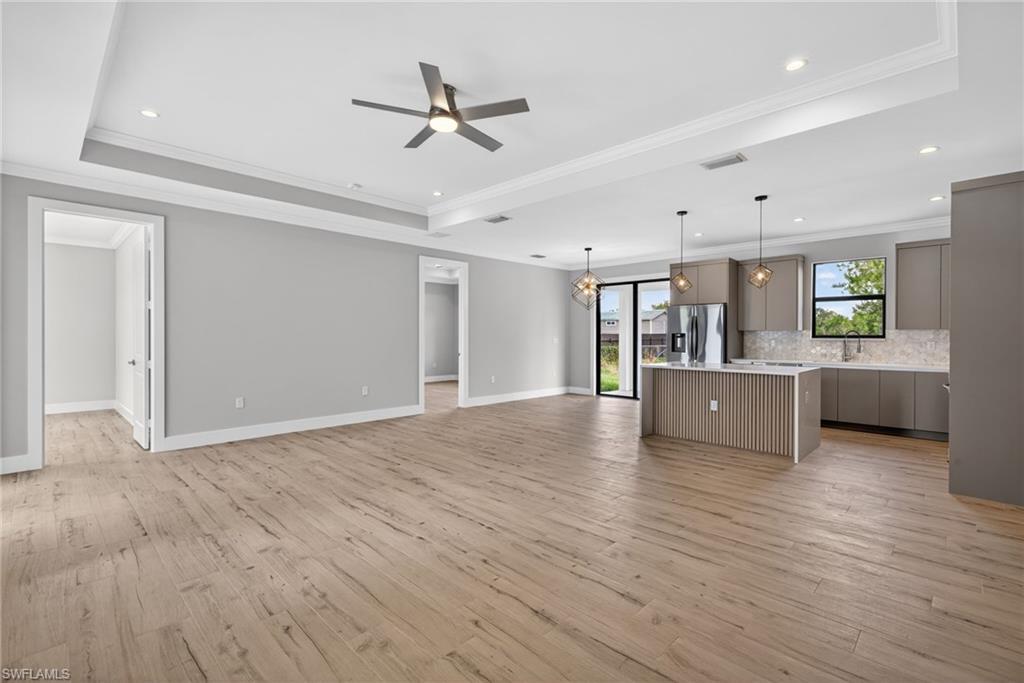 Spacious living area featuring wood-finish flooring, recessed lighting, and a tray ceiling with a modern ceiling fan