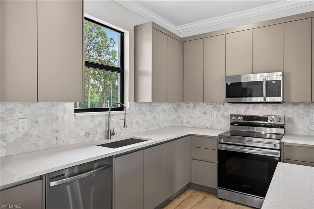 Contemporary kitchen featuring flat-panel cabinetry, a stainless steel appliance suite, and light-toned countertops