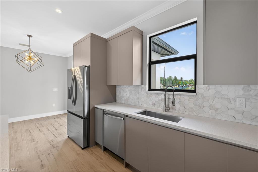 Kitchen featuring a stainless steel French door refrigerator, integrated dishwasher, and a deep undermount sink with a gooseneck faucet