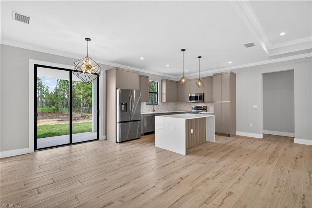 Open concept living area featuring wood-finish flooring, a contemporary kitchen with stainless steel appliances, and a central island