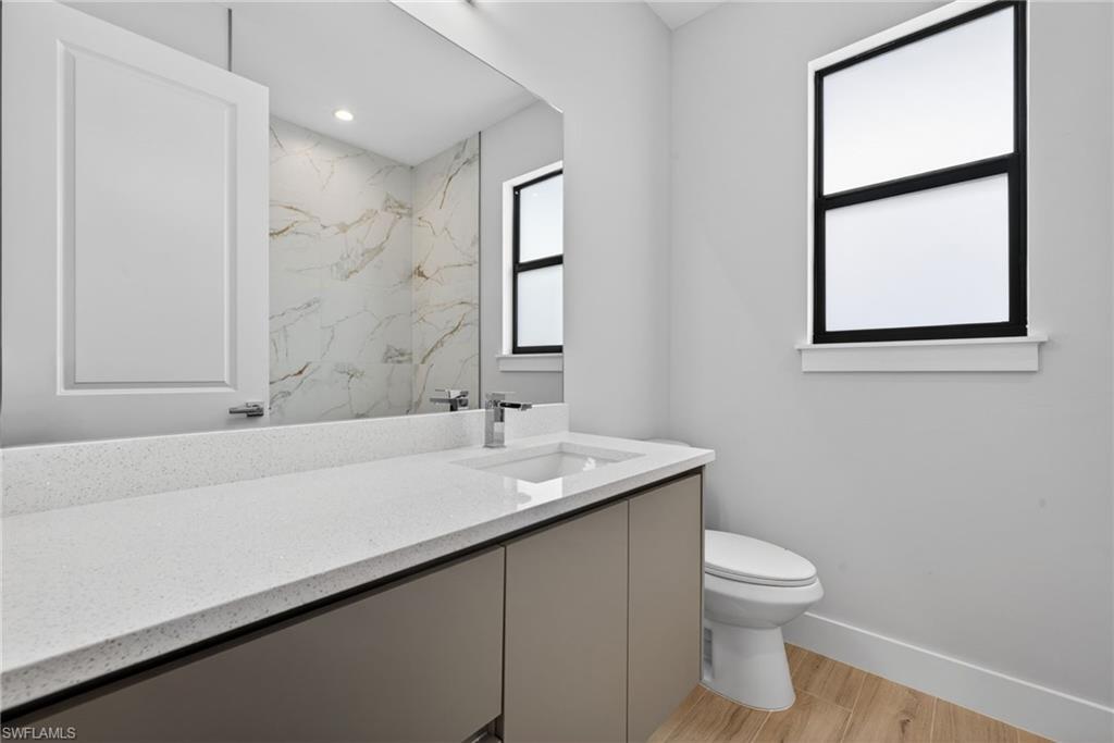 Modern bathroom featuring a contemporary vanity with a white composite countertop and integrated sink, framed by a large mirror