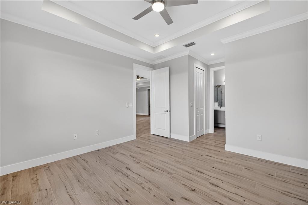 Spacious room featuring wood-finish flooring, a tray ceiling, and a ceiling fan