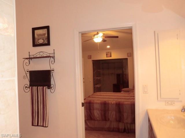 Bathroom vanity featuring a single basin sink and built-in medicine cabinet, opening to a room with a ceiling fan