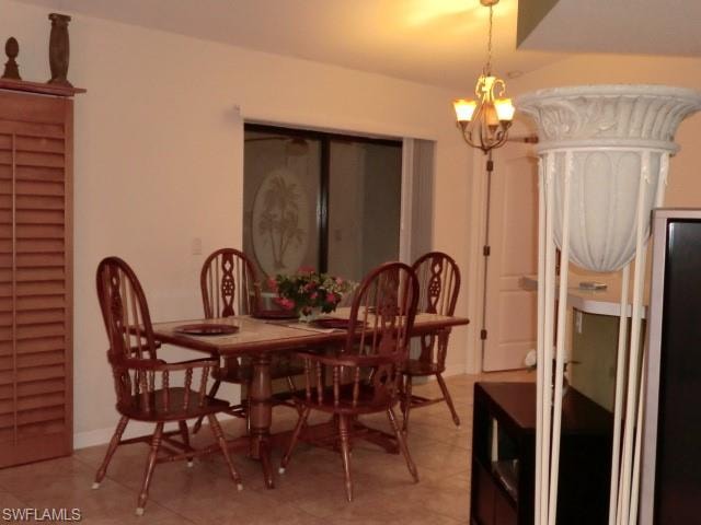 Dining area featuring light-toned tile flooring, a multi-light chandelier, and a sliding glass door with an etched glass design