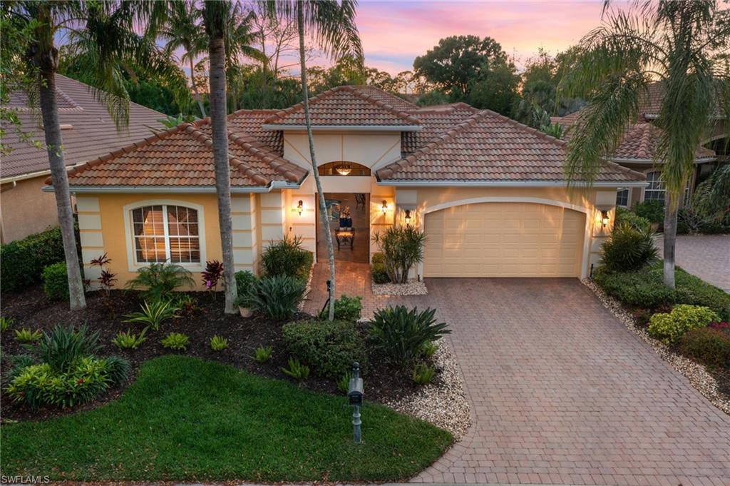 Mediterranean / spanish-style house featuring stucco siding, an attached garage, a tile roof, and decorative driveway