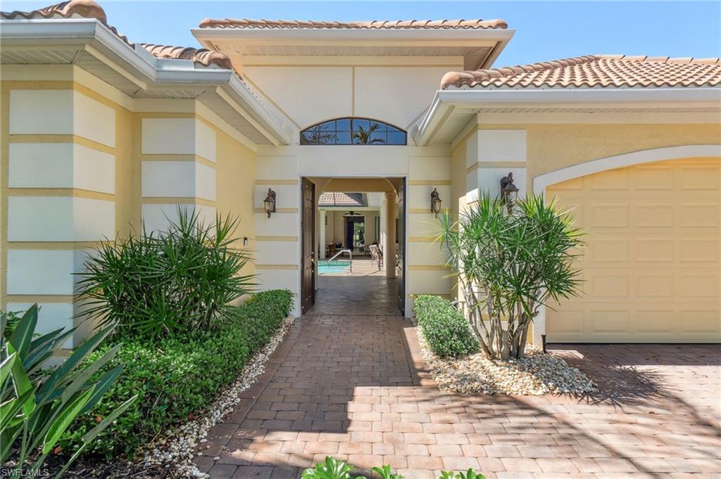 Property entrance featuring a garage, driveway, stucco siding, and a tile roof