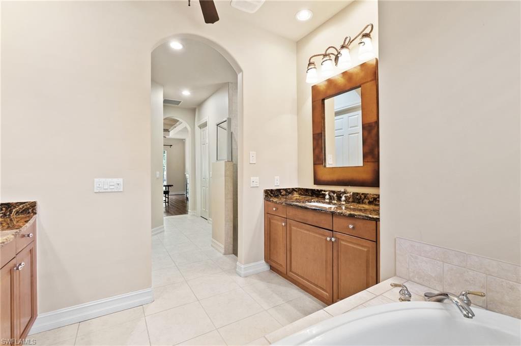 Full bath featuring tile patterned floors, a bathing tub, baseboards, ceiling fan, and vanity