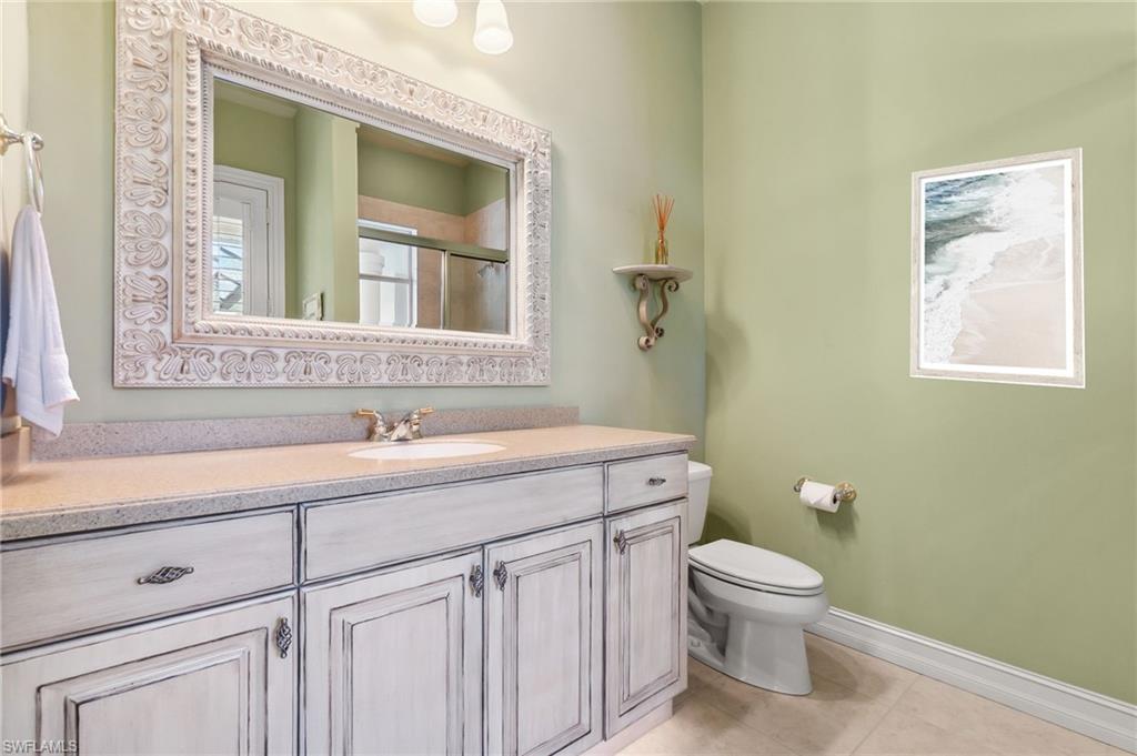Full bathroom featuring a shower with shower door, toilet, tile patterned flooring, baseboards, and vanity