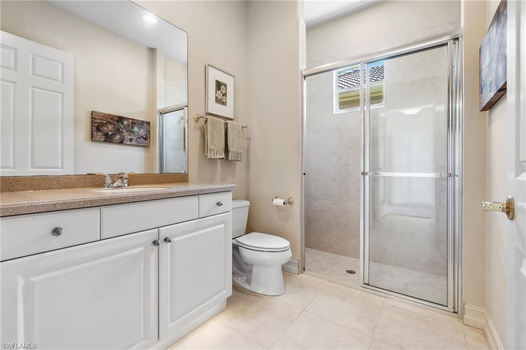 Full bath with tile patterned floors, toilet, and a stall shower