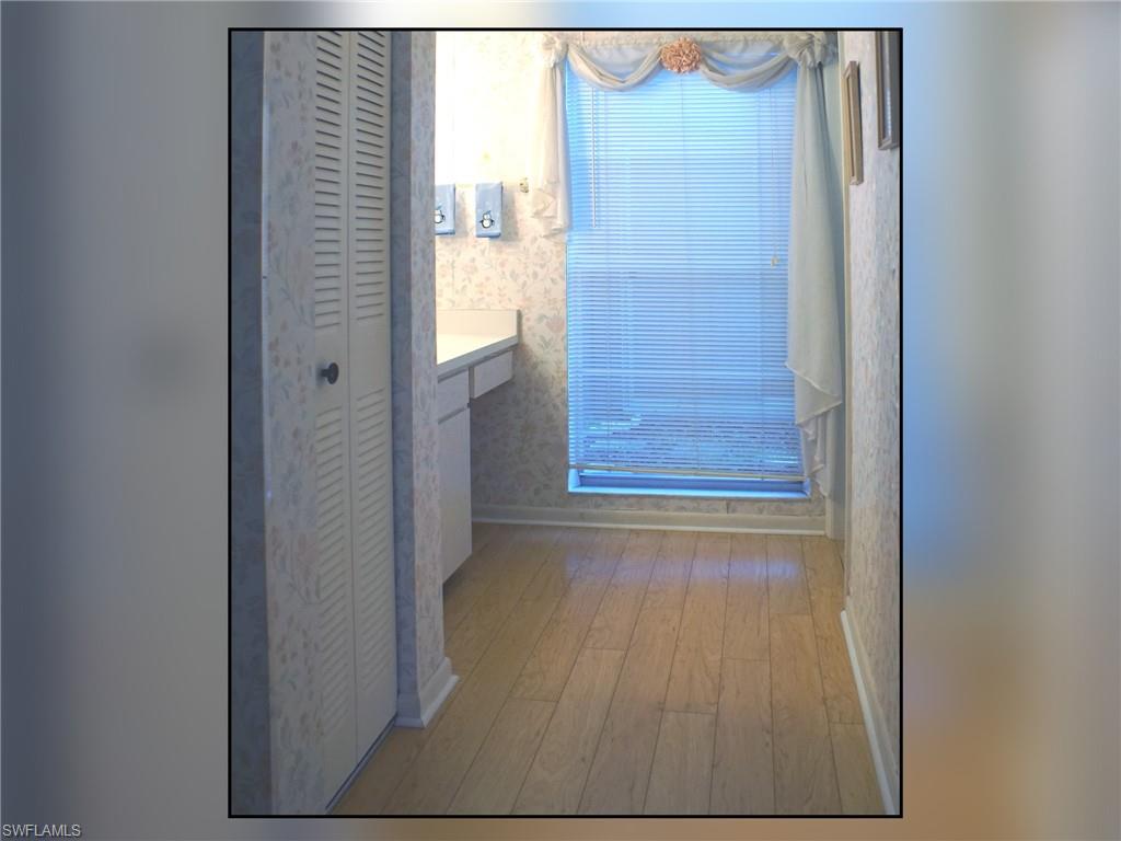Hall with light wood-type flooring and wallpapered walls
