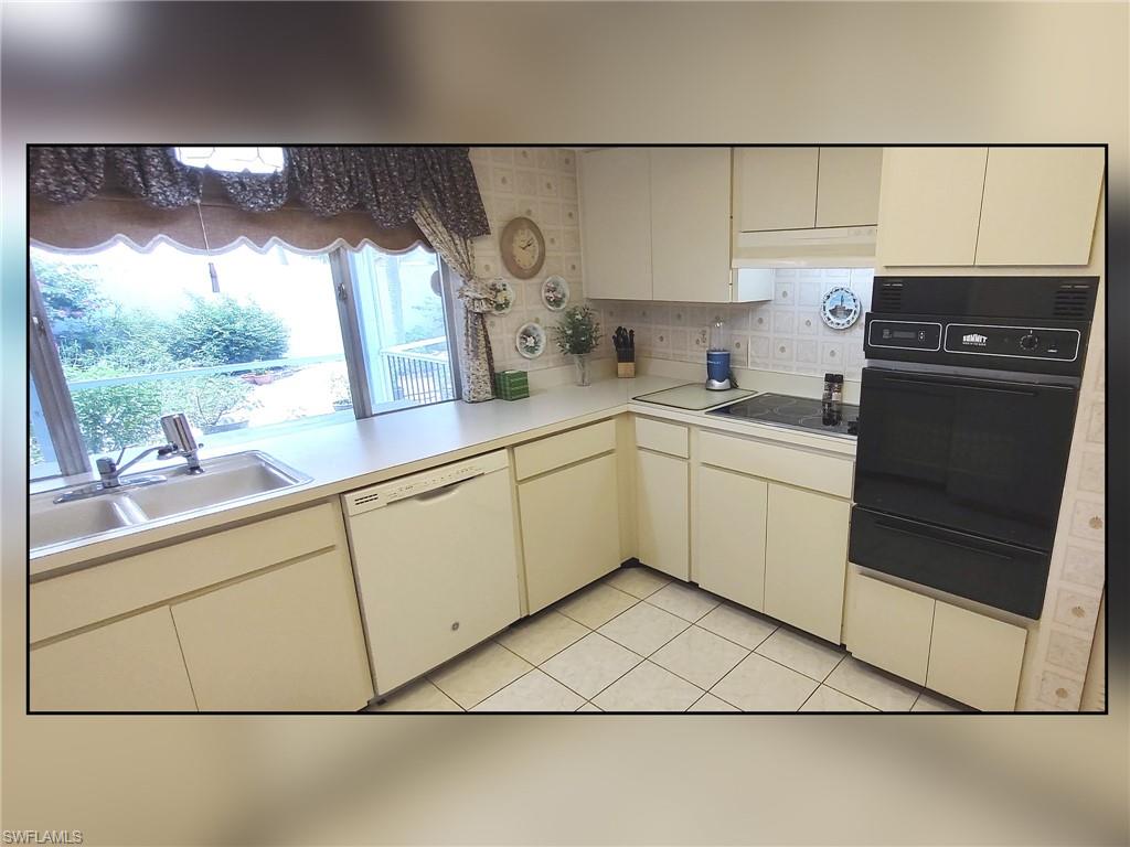 Kitchen with light countertops, tasteful backsplash, black appliances, light tile patterned flooring, and a warming drawer