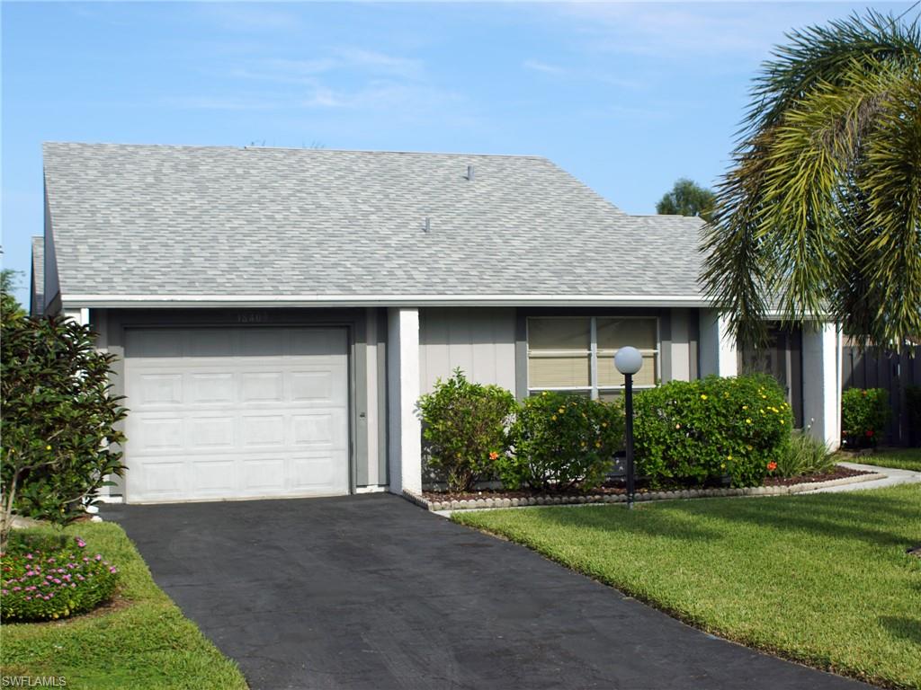 Ranch-style house with roof with shingles, driveway, an attached garage, and a front yard