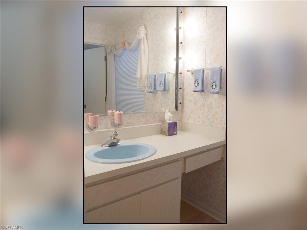 Bathroom featuring wallpapered walls and vanity