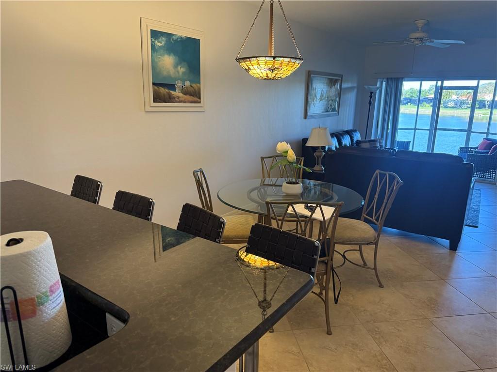 Dining space with a ceiling fan, light tile patterned flooring, and a water view