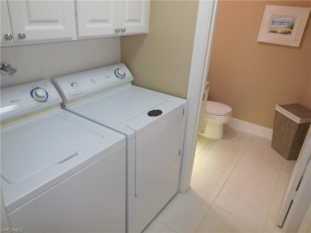 Laundry room with washer and dryer, light tile patterned flooring, and baseboards