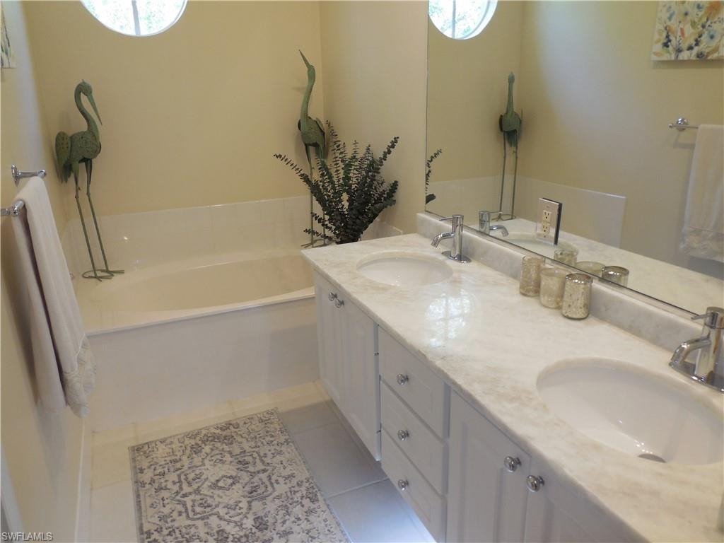 Bathroom with tile patterned floors, a bath, healthy amount of natural light, and double vanity