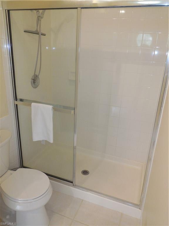 Full bathroom featuring a shower with door and toilet