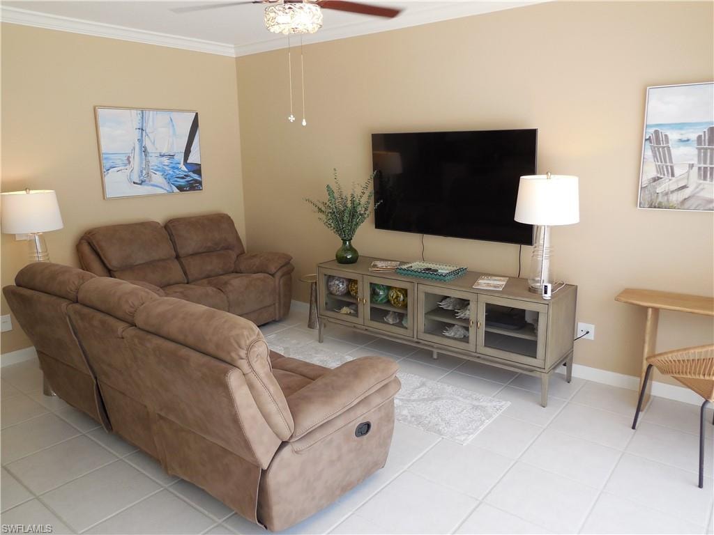 Living room with ornamental molding, a ceiling fan, baseboards, and tile patterned flooring