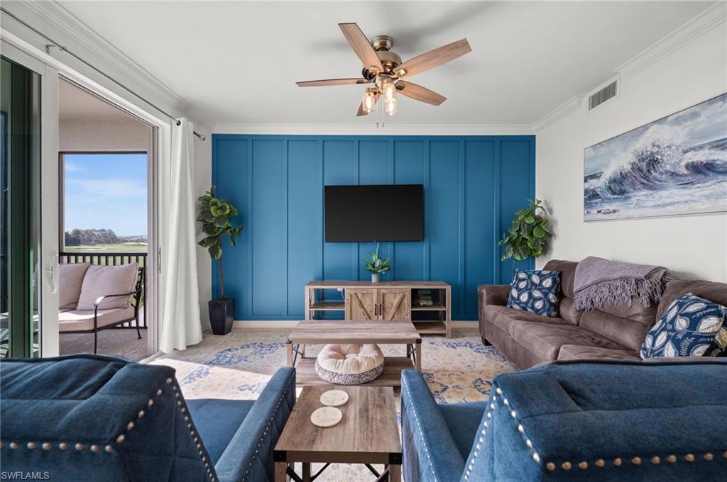 Open-concept living area featuring a prominent accent wall with vertical paneling, a ceiling fan with integrated lighting, and crown molding