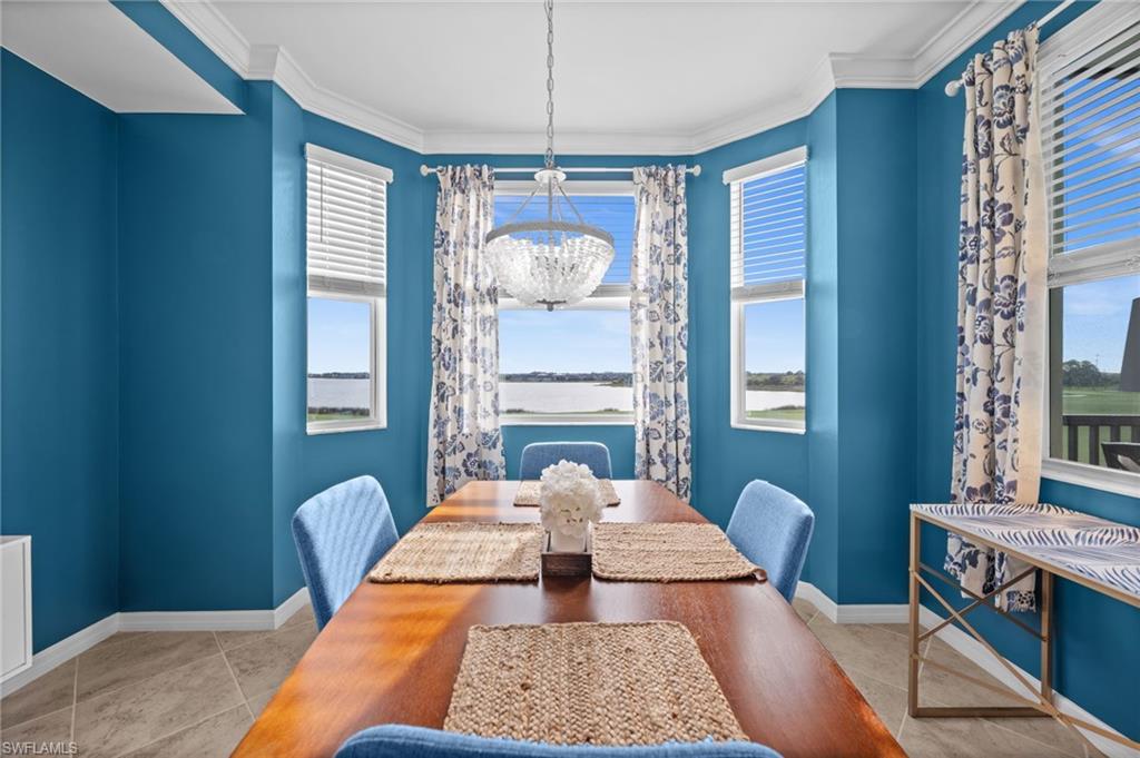 Bay window dining area featuring a crystal chandelier, crown molding, and tile flooring