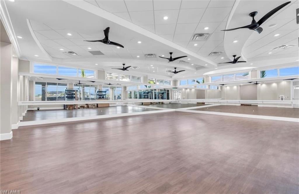 Spacious open room featuring wood-finish flooring, full-height wall mirrors, and integrated ballet barres