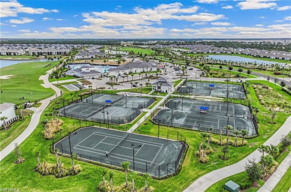 Multiple tennis courts surrounded by manicured landscaping