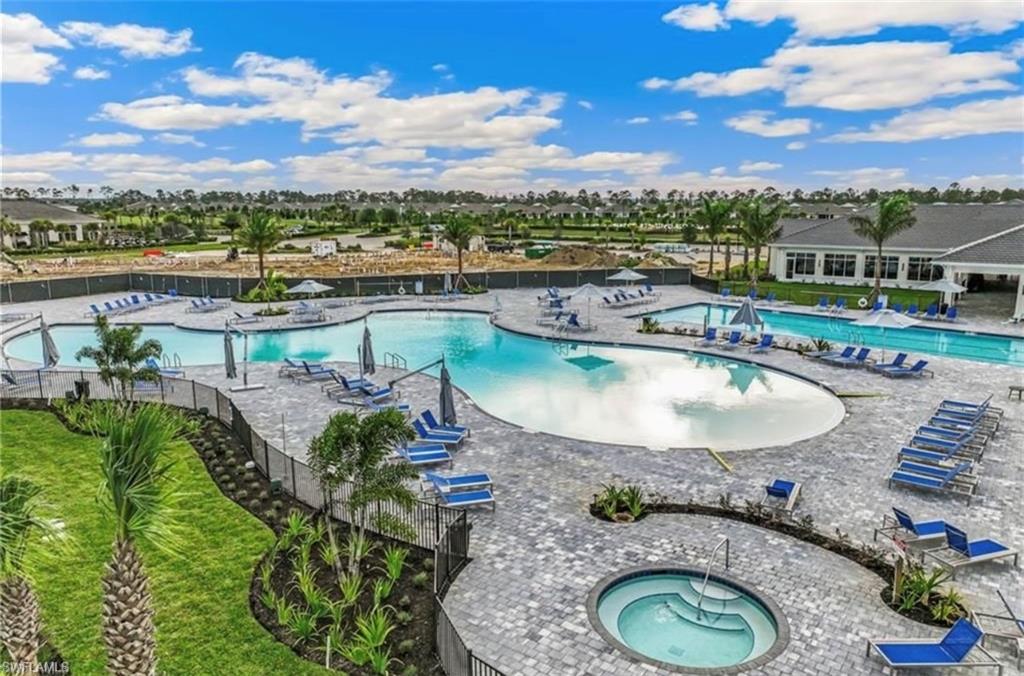 Resort-style pool area featuring multiple swimming pools, a separate spa, and extensive paver decking