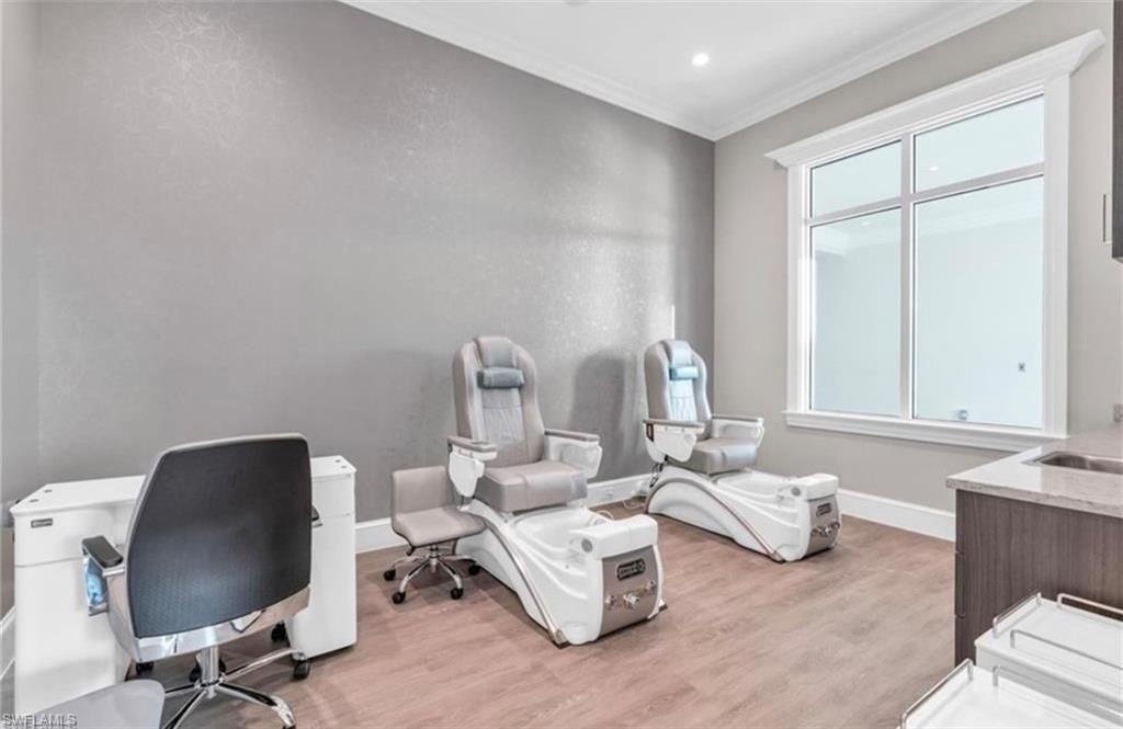 Room featuring wood-finish flooring, a large window with white trim, and crown molding