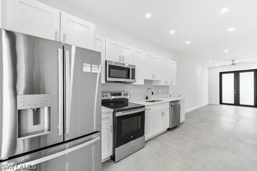 Kitchen #1 featuring appliances with stainless steel finishes, white cabinetry, light countertops, french doors, and recessed lighting