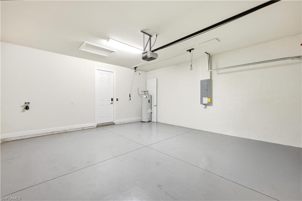 Spacious garage featuring a durable concrete floor, an overhead garage door opener, and a panel door for interior access