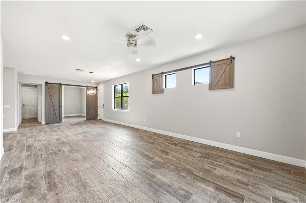 Spacious interior featuring wood-finish tile flooring, recessed lighting, and a ceiling fan