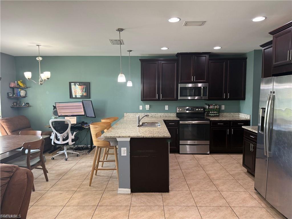 Kitchen featuring dark wood cabinetry, stainless steel appliances, granite countertops, and a central island with a breakfast bar
