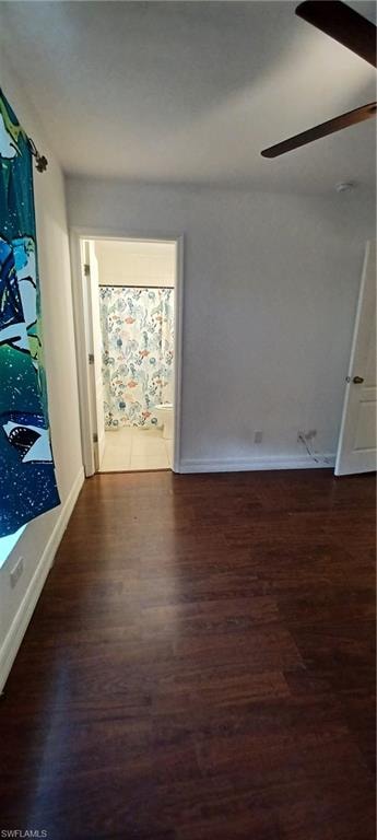 Room featuring dark wood-finish flooring, white baseboards, and a ceiling fan