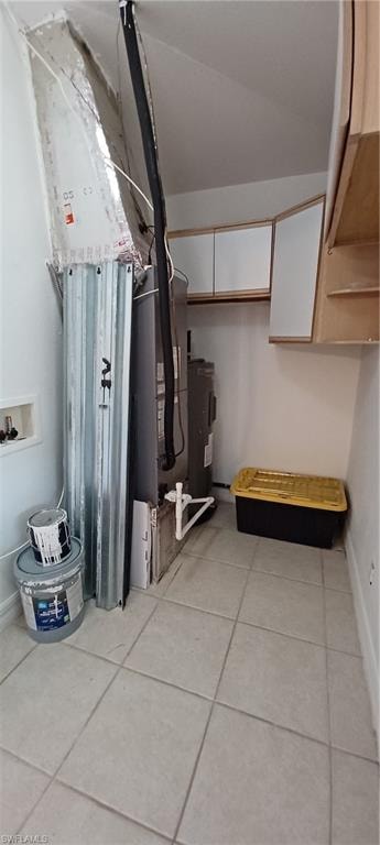 Laundry room in home, with light-toned tiled flooring, wall-mounted cabinetry, and A/C Unit & Hot Water Heater. Hurricane Shutters storage.