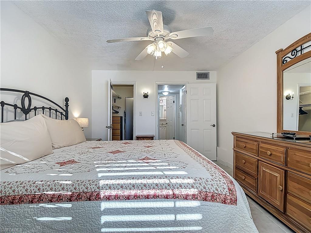 Bedroom with a textured ceiling, a ceiling fan, and light tile patterned floors