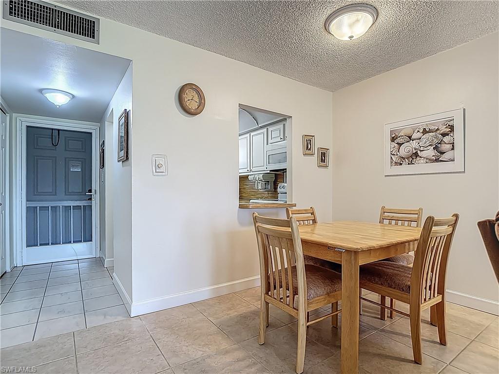 Dining room featuring light tile patterned flooring, a textured ceiling, and baseboards