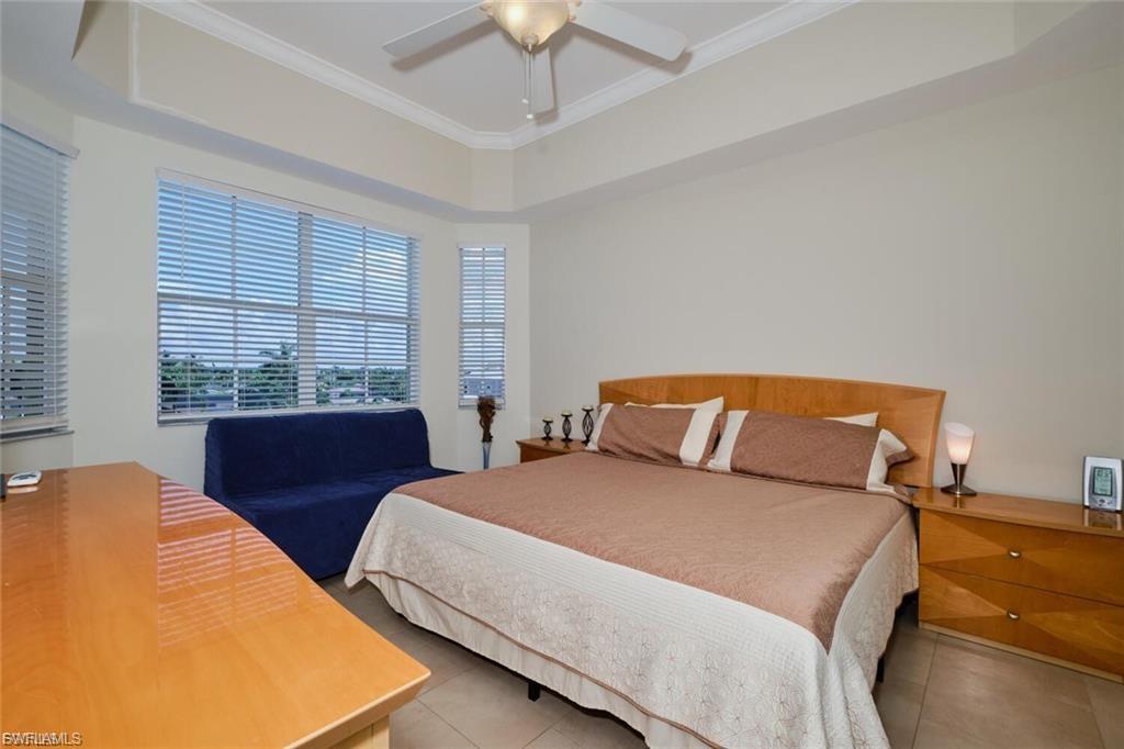 Spacious room featuring multiple large windows with horizontal blinds, tray ceiling with crown molding, and a ceiling fan