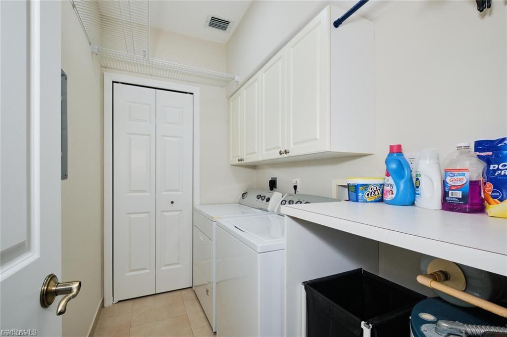 Dedicated laundry area featuring a washer and dryer, upper cabinetry, a utility shelf, and tile flooring