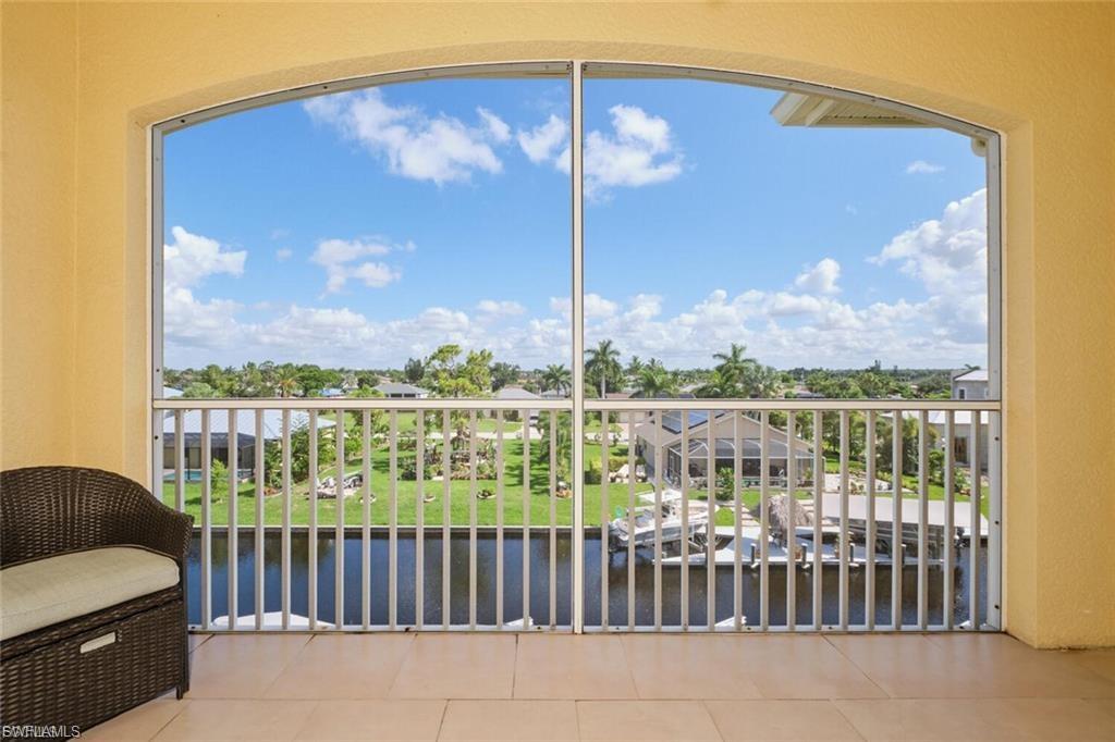 Screened balcony featuring a water view, tiled flooring, railing, and an arched frame