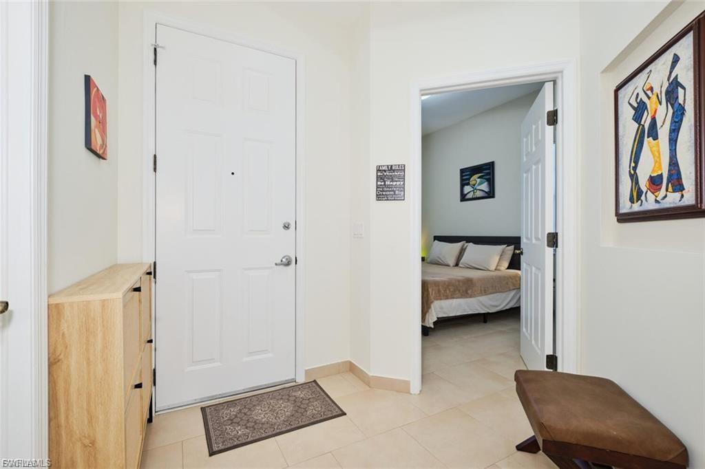 Entryway featuring light-toned tile flooring and a paneled white door with a polished chrome handle