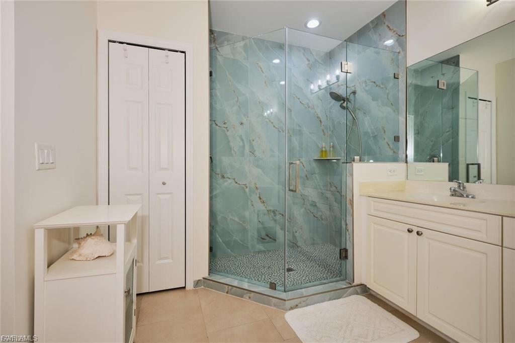 Glass-enclosed shower with patterned wall tile and pebbled floor
