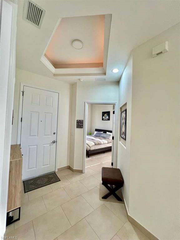 Entryway featuring light-toned large format tile flooring and a recessed ceiling detail with integrated lighting